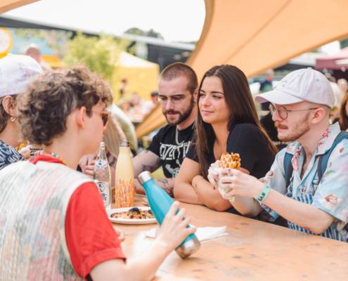 Mensen die samen eten aan tafel op Vegan Summer Fest